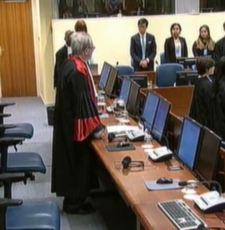 Video feed snapshot of a status conference with the President, Judge Carmel Agius, as presiding judge.