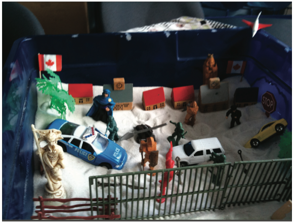 This sand tray, dominated by symbols of violence, security and barricades, was created by a 12-year-old boy while he was detained with his mother and older sister. The family’s asylum claim was refused and, at the time of the interview in 2011, they had been detained at the IHC for seven months. The boy appeared to have developed multiple psychiatric symptoms during detention. © Rachel Kronick