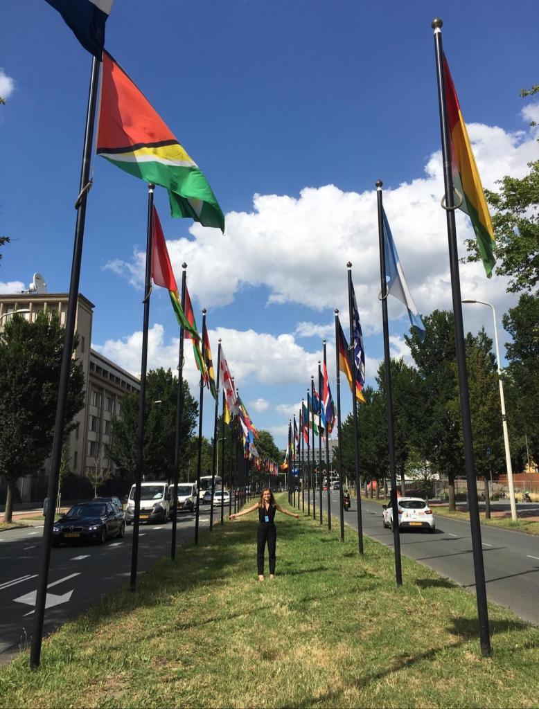 IHRP Summer Fellow Teodora Pasca between flags at The Hague's International Quarter
